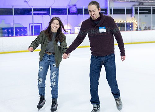 A man and woman skating on an ice rink.