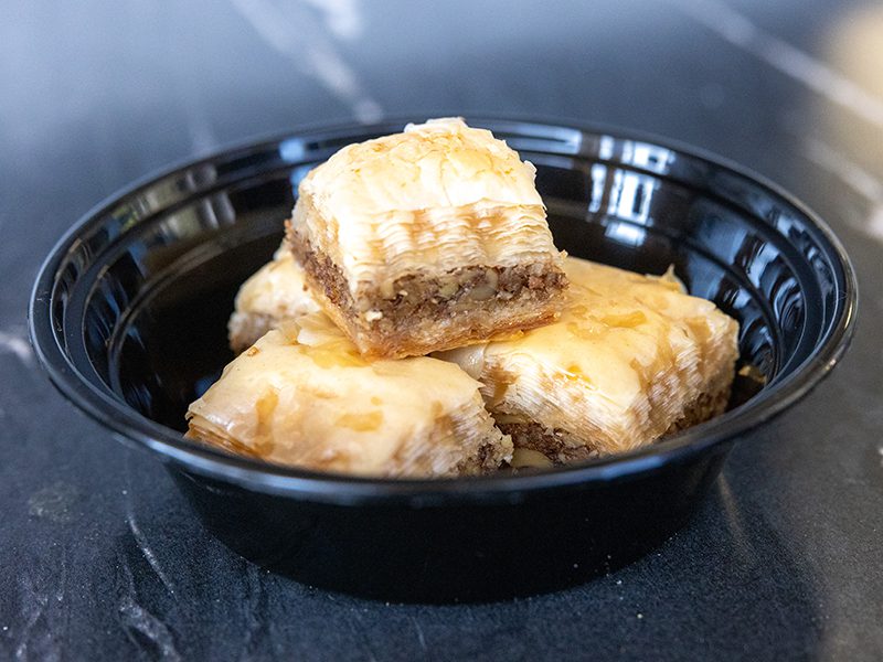 Baklava in a black bowl on a marble table.
