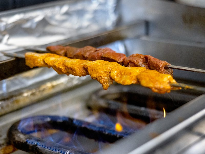 Skewers of meat being cooked on a grill.