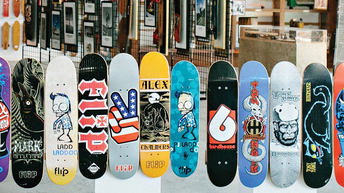 A row of colorful skateboard decks displayed vertically in a store, each showcasing unique graphics and designs.