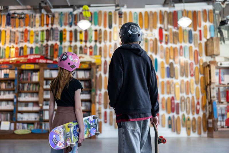 Two people standing in front of a skateboard shop.