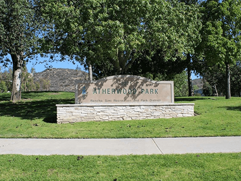 Atherwood Park sign with grass, trees, and a path