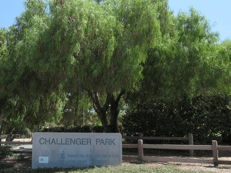 Challenger Park sign with trees and a path