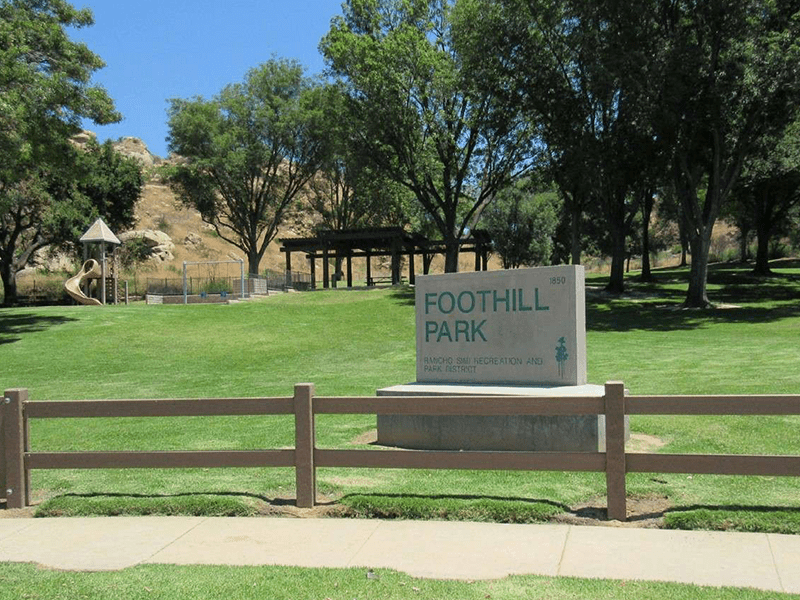 Foothill Park sign with grass, trees, and a path