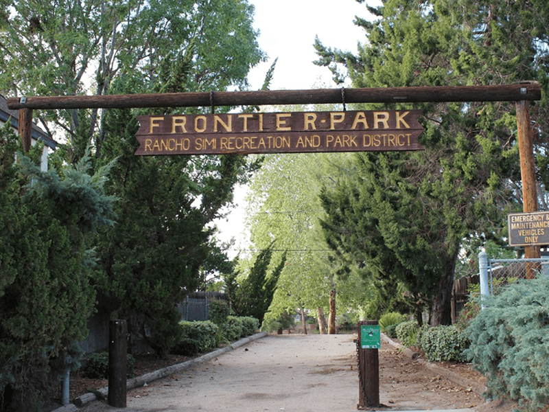 Frontier Park sign over a path lined with trees and bushes