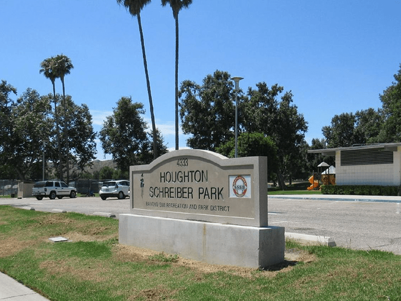 Houghton Schreiber Park sign with grass and the road in the background