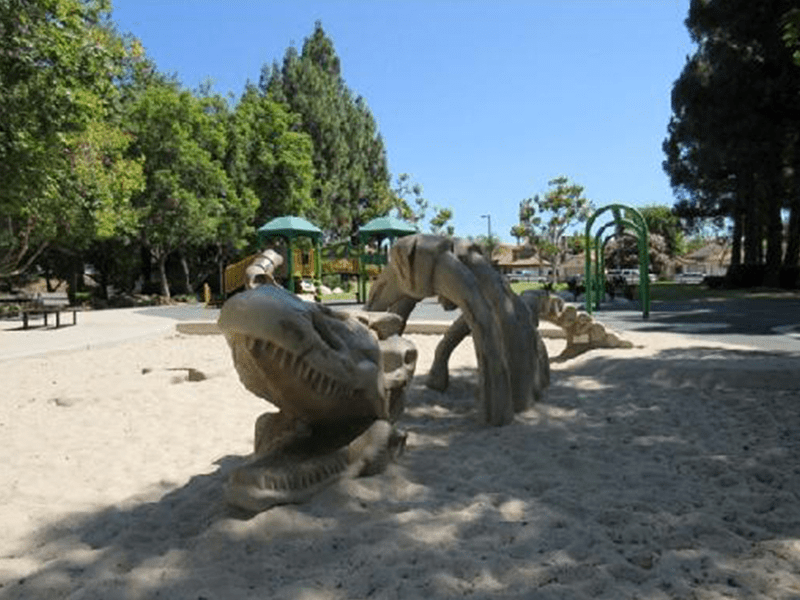 Mayfair Park play area with toy dinosaur bones and a playground