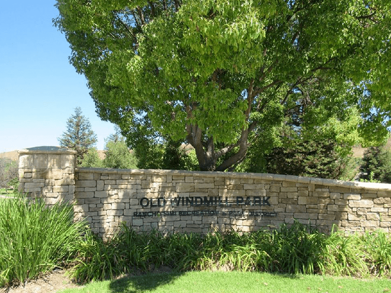 Old Windmill Park sign with grass, trees, and plants surrounding