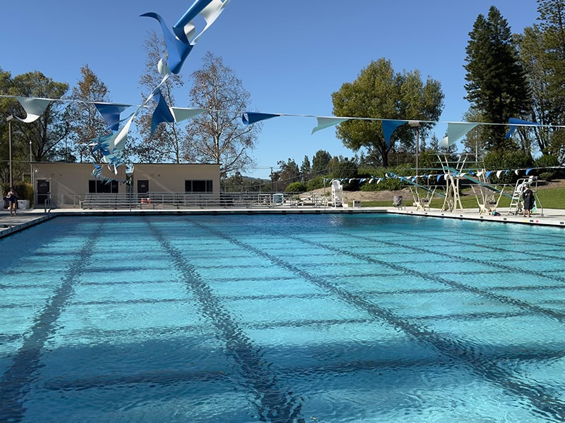 Outdoor swimming pool at Rancho Simi Community Pool with blue sky and trees.