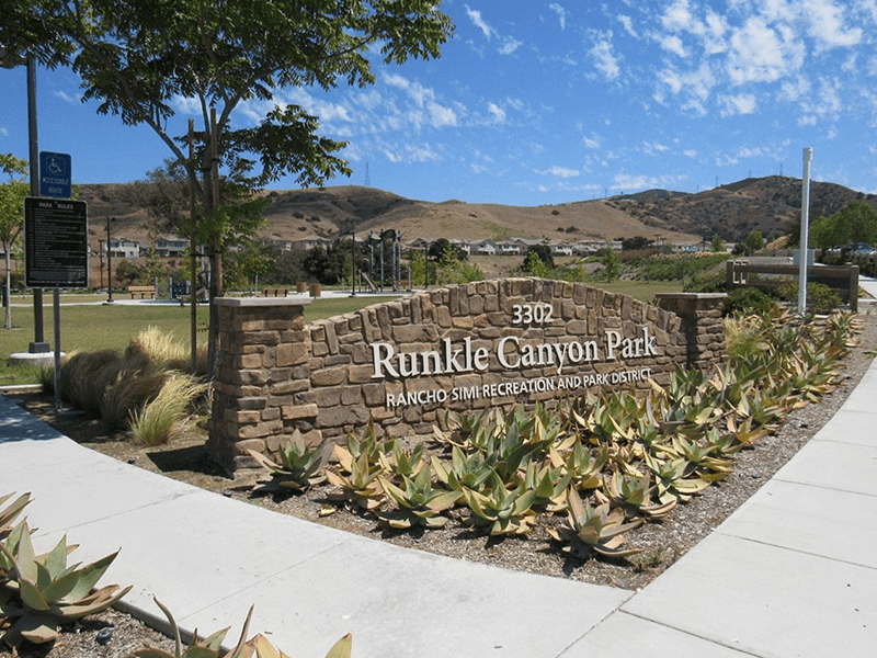 Runkle Canyon Park sign with plants and a walking path around it