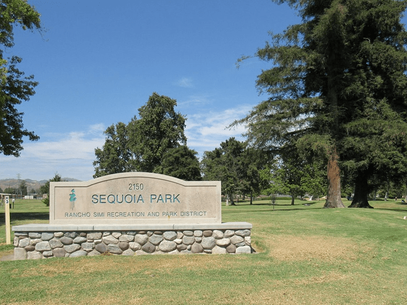 Sequoia Park sign in front of a grass field and trees