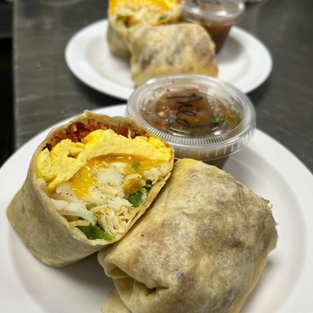 Two breakfast burritos are sitting on plates.