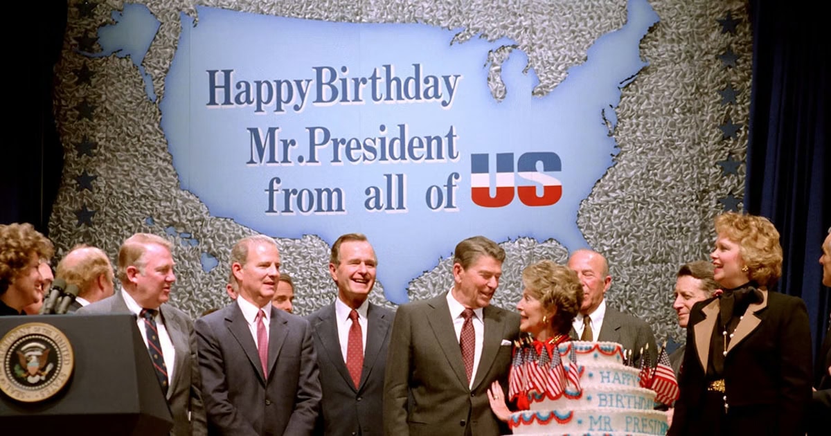 Happy Birthday Mr. President celebration with U.S. flag backdrop and smiling officials.