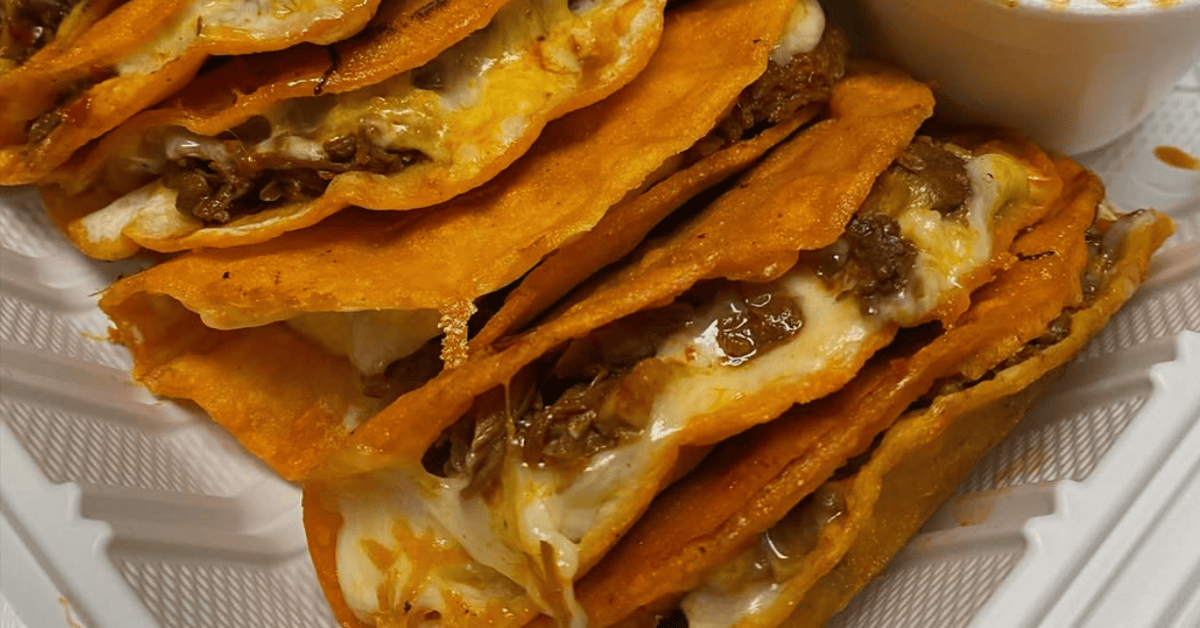 A delicious plate of beef and cheese nachos with lime wedges and salsa on the side.