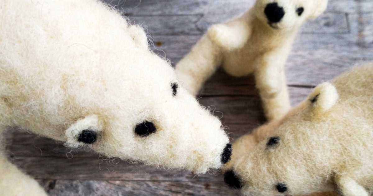 Close-up of handmade felted polar bears during needle felting craft session.