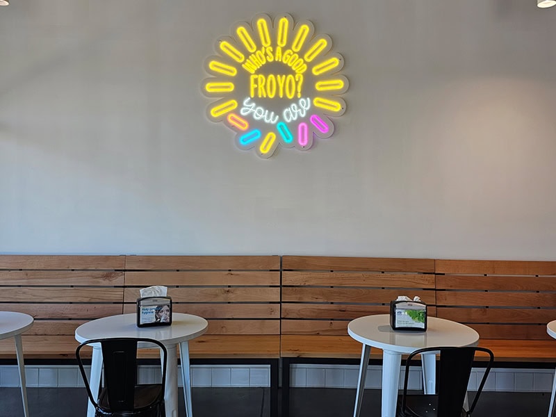 Colorful neon sign reading 'Who has a good Froyo?' inside Froyo & Fido.