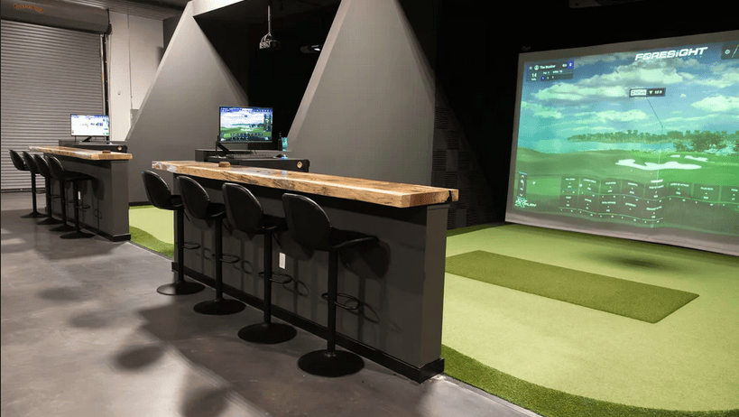 Indoor golf simulator with seating area at Visit Simi Valley entertainment center.