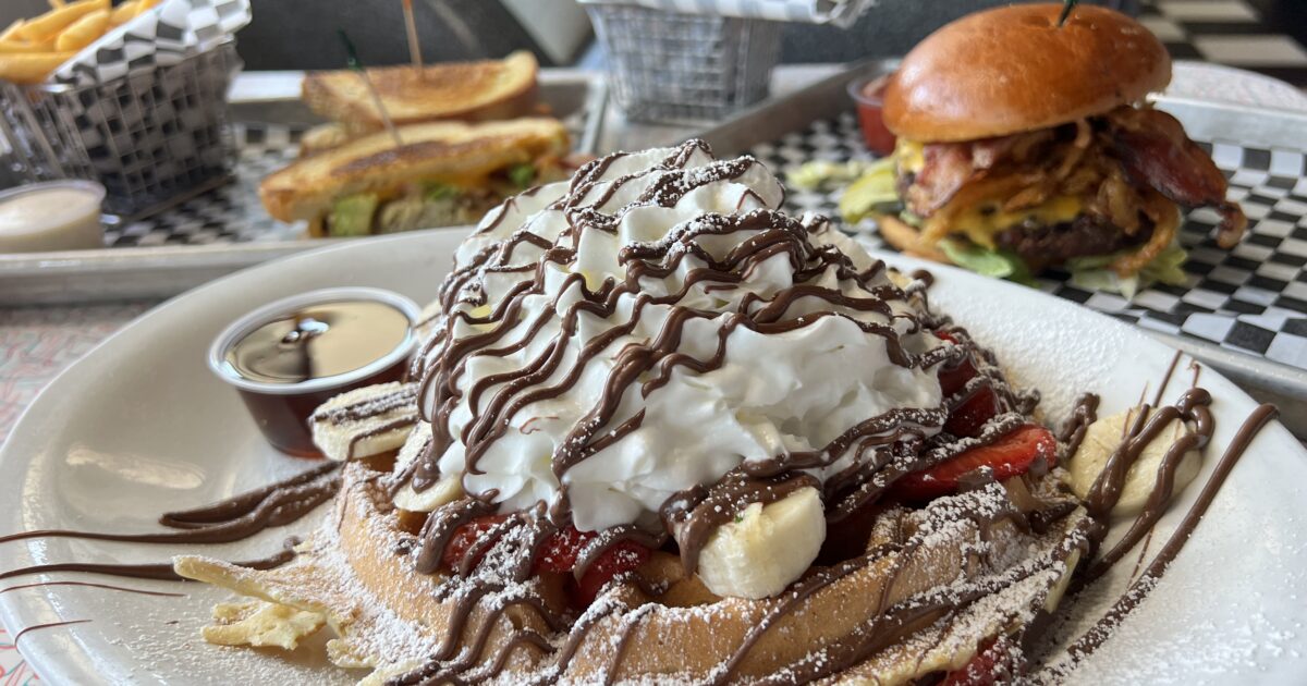 Photo of a waffle, burger and sandwich on a table