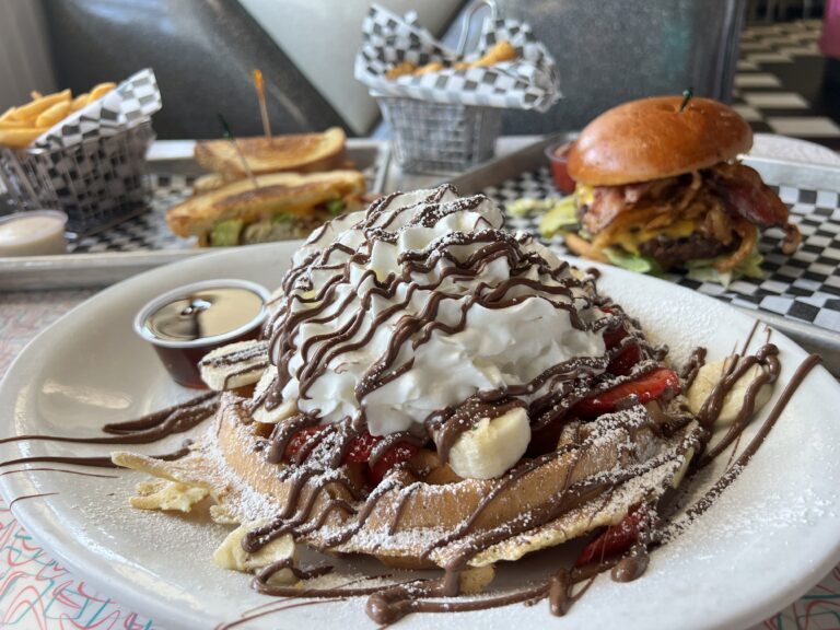 Photo of a waffle, burger and sandwich on a table