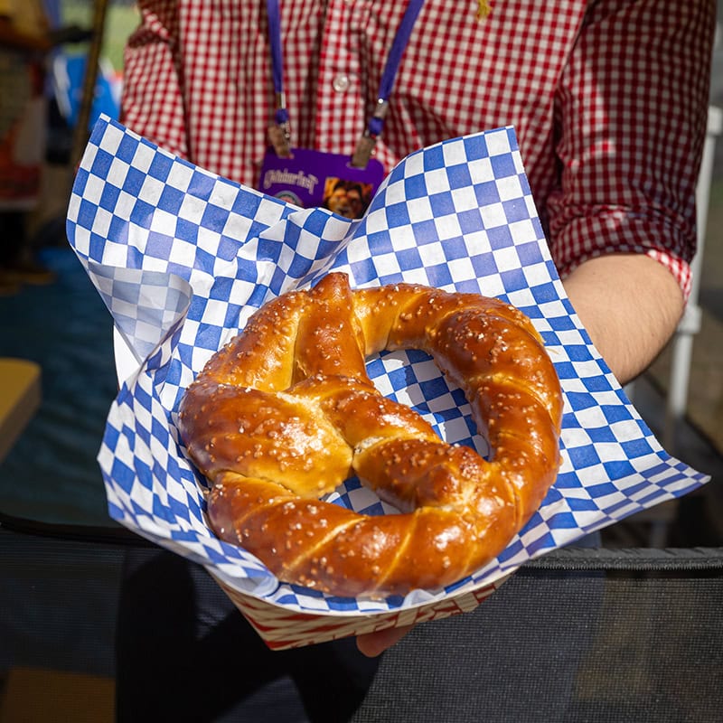 Person holding a freshly baked pretzel at Simi Valley Oktoberfest event.