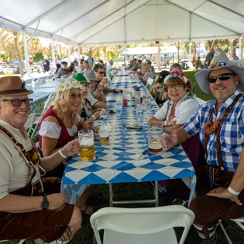 People enjoying Oktoberfest under a large tent with traditional attire and beer.