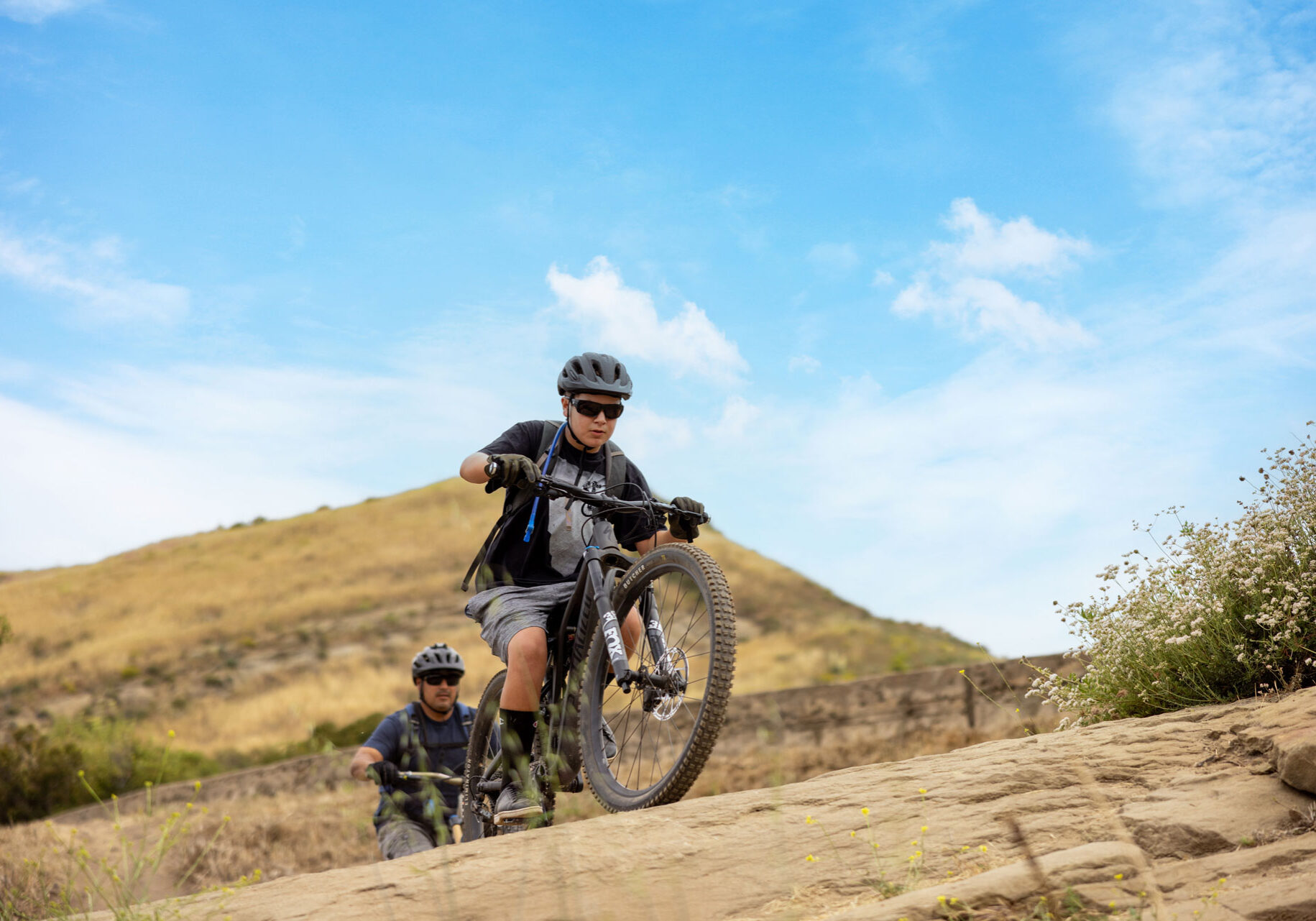 Two mountain bikers riding down a rocky trail.